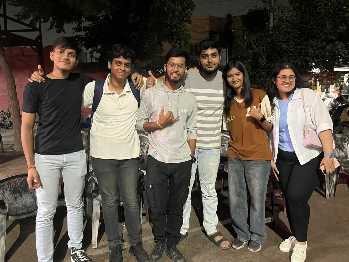 Six members outside a roadside cafe at night.